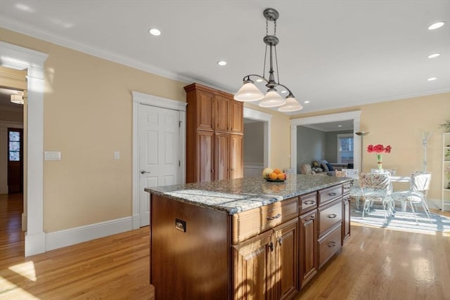 kitchen featuring light hardwood / wood-style floors, a center island, crown molding, and decorative light fixtures