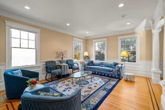 living room featuring decorative columns, crown molding, and wood-type flooring