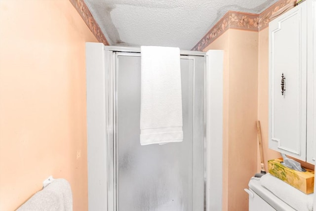 bathroom with toilet, a stall shower, and a textured ceiling