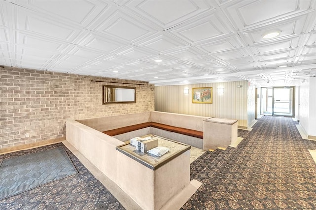 interior space with baseboards, an ornate ceiling, and brick wall