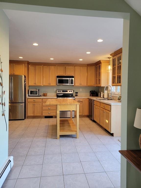 kitchen featuring a baseboard radiator, appliances with stainless steel finishes, decorative light fixtures, sink, and light tile patterned flooring