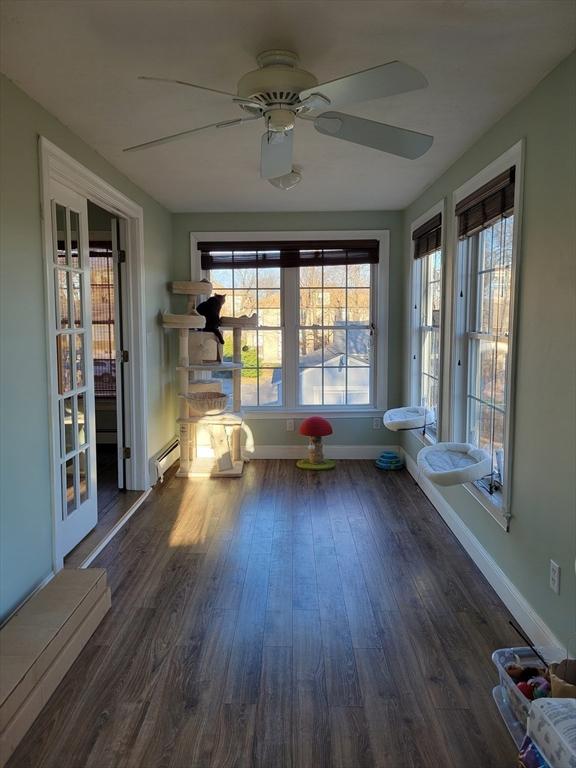 unfurnished sunroom featuring ceiling fan, a healthy amount of sunlight, and a baseboard heating unit