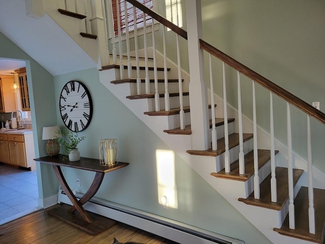 stairway with sink, hardwood / wood-style floors, and a baseboard heating unit