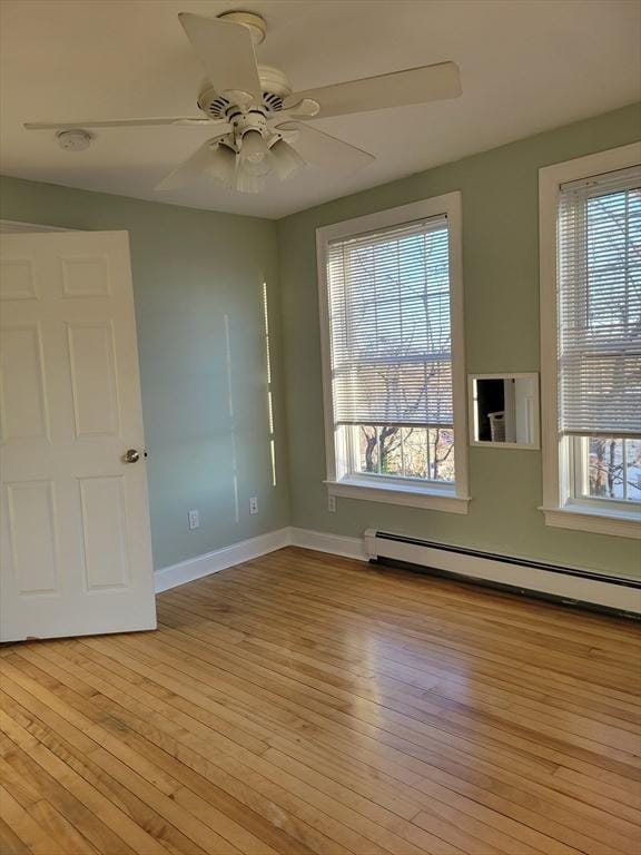 empty room featuring a baseboard radiator, a healthy amount of sunlight, light hardwood / wood-style flooring, and ceiling fan