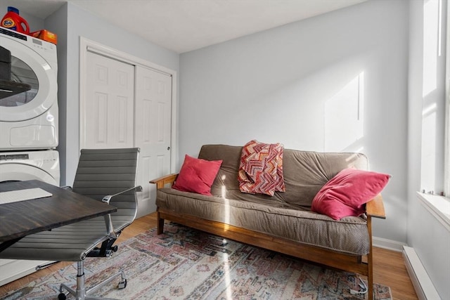 interior space featuring baseboard heating, wood-type flooring, and stacked washer / drying machine