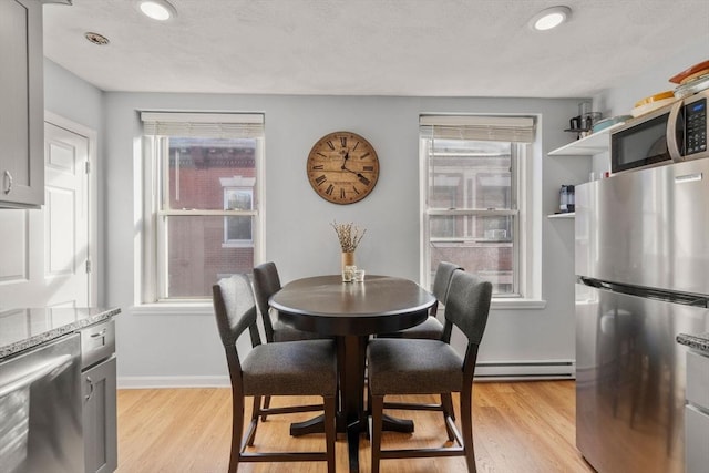 dining area with light hardwood / wood-style floors, a wealth of natural light, and a baseboard radiator