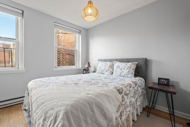 bedroom with light hardwood / wood-style floors and a baseboard radiator