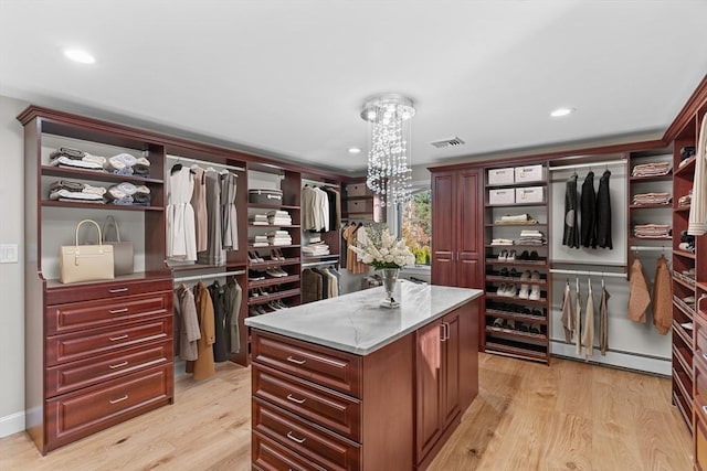 spacious closet with a chandelier, a baseboard radiator, and light hardwood / wood-style floors