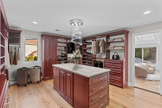 kitchen with a kitchen island, light hardwood / wood-style floors, radiator, and an inviting chandelier