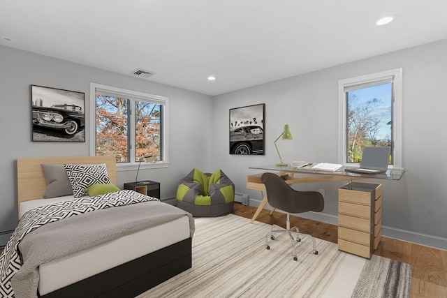 bedroom featuring light hardwood / wood-style flooring and a baseboard heating unit