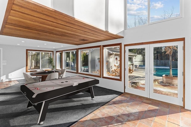 game room with french doors, a high ceiling, and a baseboard heating unit