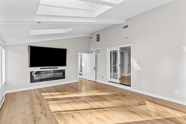 unfurnished living room featuring hardwood / wood-style floors, lofted ceiling with skylight, and baseboard heating