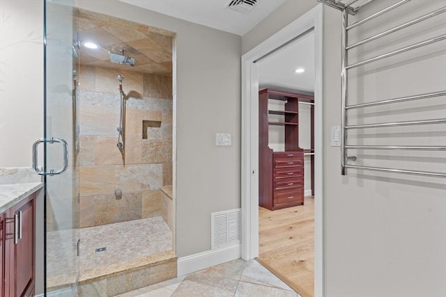 bathroom with tile patterned flooring, vanity, and walk in shower