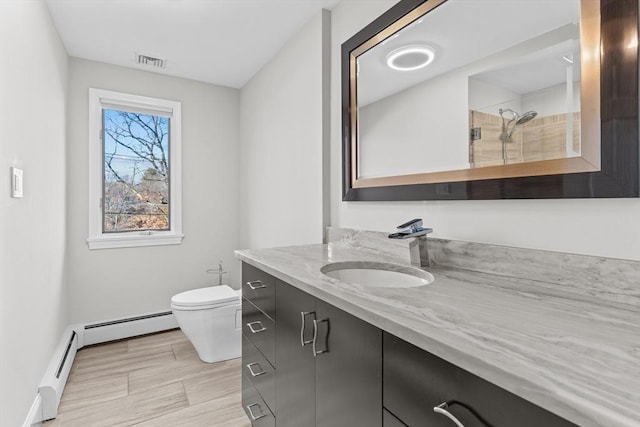 bathroom featuring vanity, toilet, a shower, and a baseboard radiator