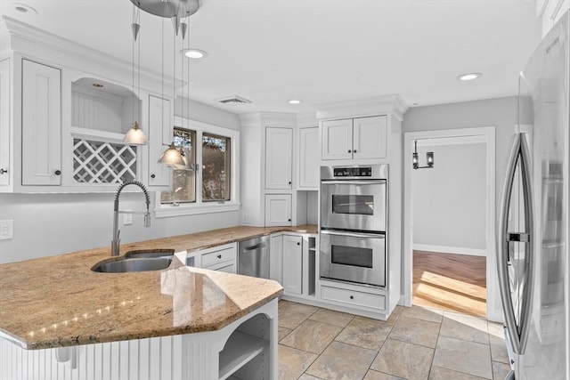 kitchen with decorative light fixtures, stainless steel appliances, white cabinetry, and sink