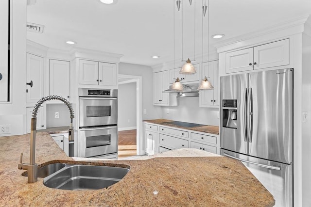 kitchen featuring light stone countertops, stainless steel appliances, sink, pendant lighting, and white cabinets