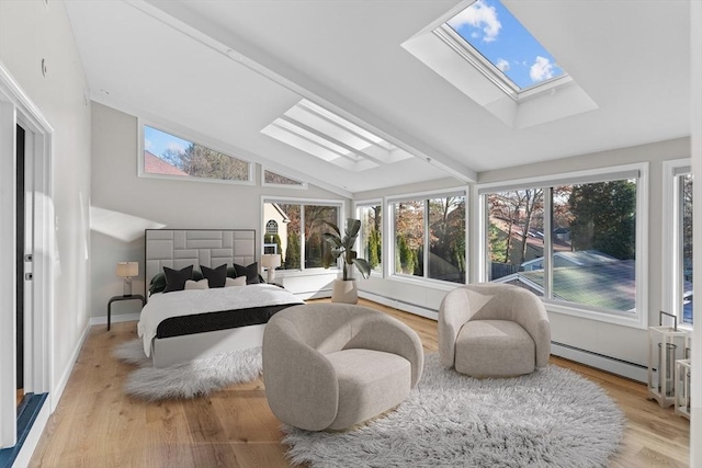 bedroom featuring light hardwood / wood-style flooring, lofted ceiling with skylight, and a baseboard heating unit