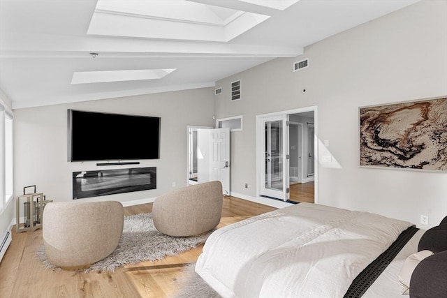 bedroom with hardwood / wood-style floors, lofted ceiling with skylight, multiple windows, and a baseboard heating unit