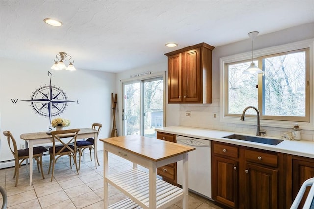 kitchen with sink, decorative light fixtures, light tile patterned floors, dishwasher, and backsplash