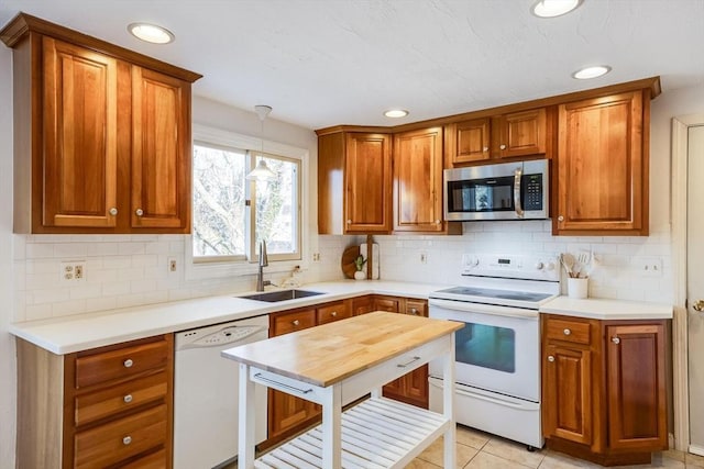 kitchen featuring pendant lighting, sink, white appliances, light tile patterned floors, and tasteful backsplash