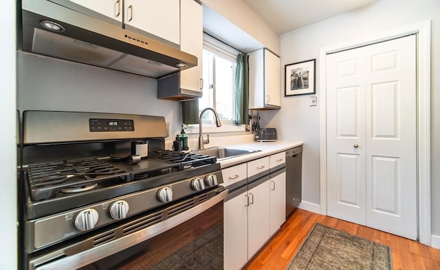 kitchen with a sink, stainless steel appliances, under cabinet range hood, and white cabinets