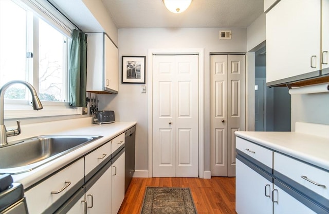 kitchen with a sink, dark wood finished floors, white cabinets, and light countertops