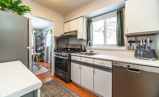 kitchen with light countertops, appliances with stainless steel finishes, white cabinets, and under cabinet range hood