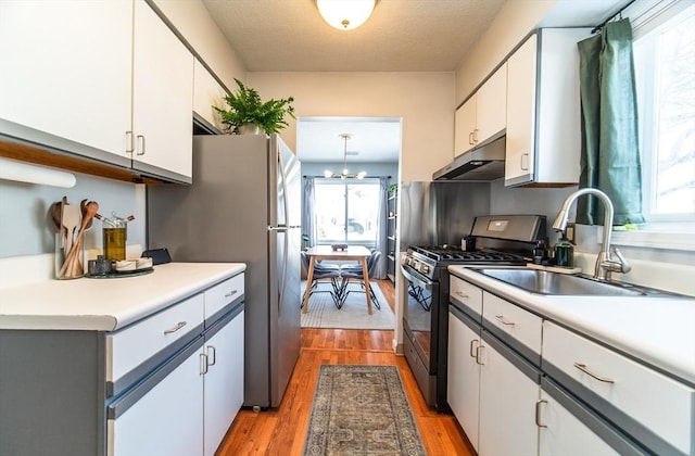 kitchen with light countertops, white cabinets, under cabinet range hood, and black range with gas stovetop