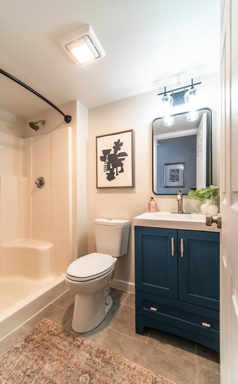 full bath featuring toilet, tile patterned flooring, a shower, and vanity