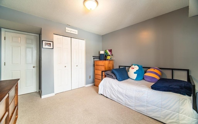 bedroom featuring baseboards, a closet, a textured ceiling, and light colored carpet