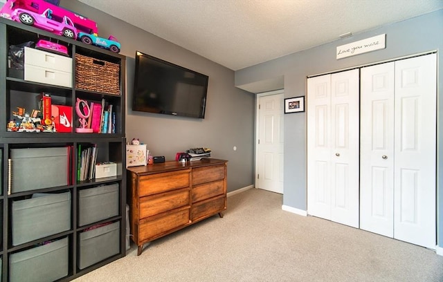 bedroom featuring light carpet, a textured ceiling, baseboards, and a closet