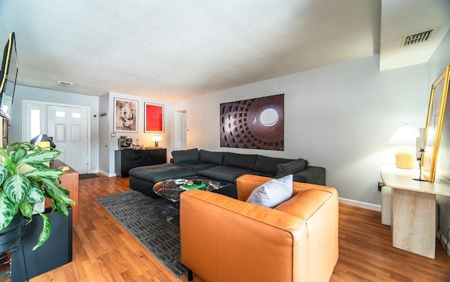 living room featuring baseboards, visible vents, and wood finished floors