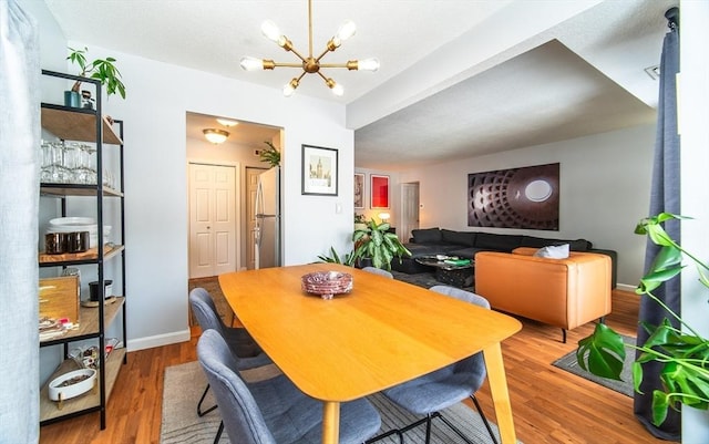 dining space with a chandelier, wood finished floors, and baseboards