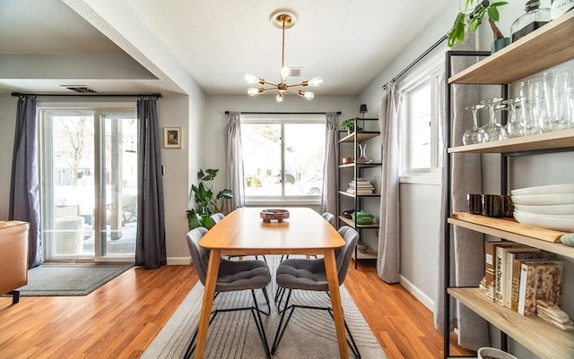 dining area with a notable chandelier, plenty of natural light, and wood finished floors