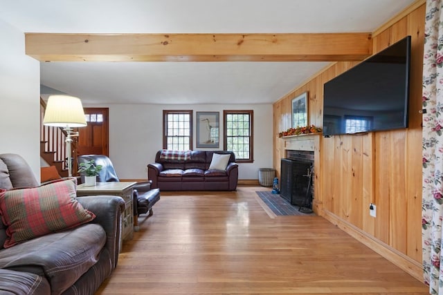 living room featuring beamed ceiling, wood walls, and wood-type flooring