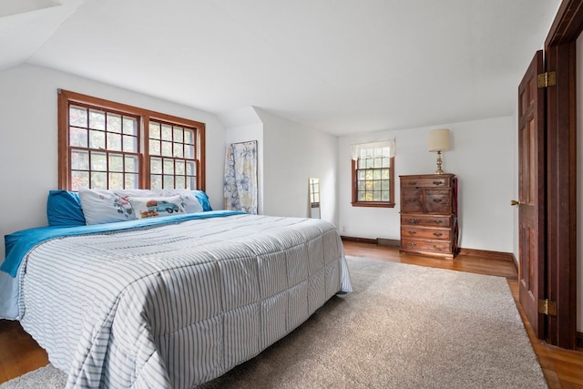 bedroom featuring hardwood / wood-style flooring, lofted ceiling, and multiple windows