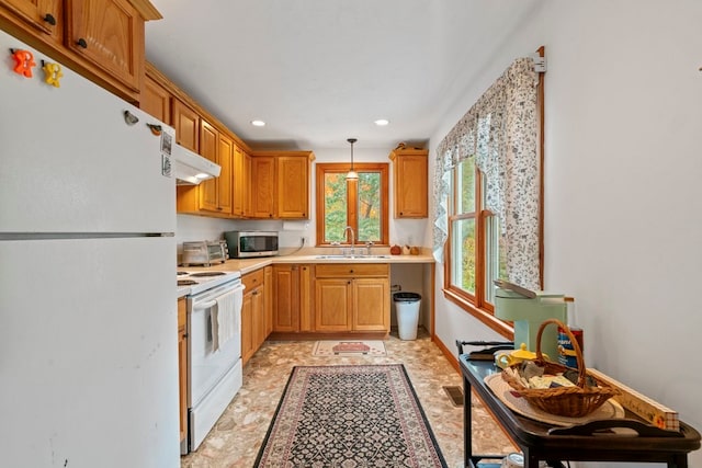 kitchen with pendant lighting, white appliances, and sink