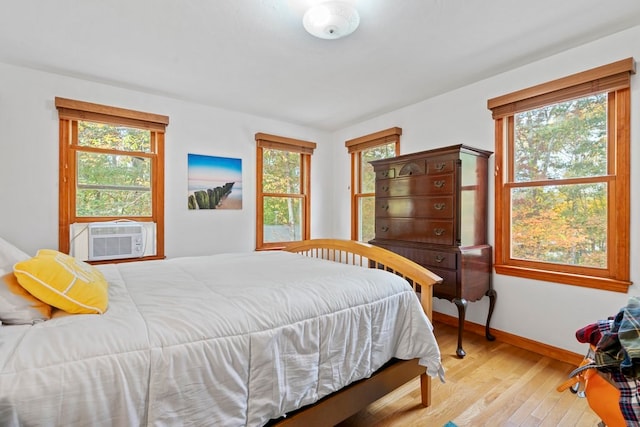 bedroom with cooling unit, light hardwood / wood-style flooring, and multiple windows