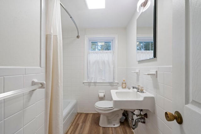 full bathroom with shower / bath combo with shower curtain, hardwood / wood-style floors, tile walls, and toilet