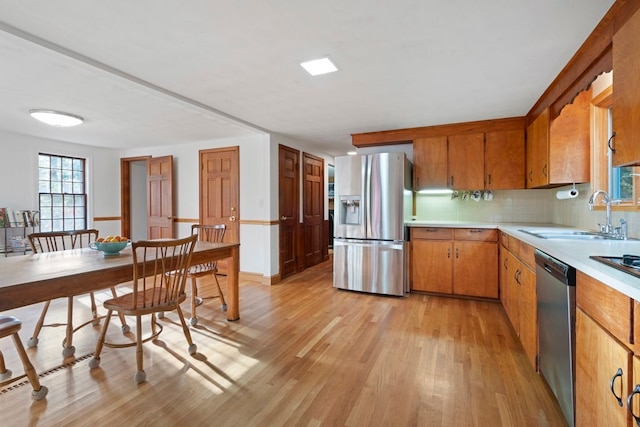 kitchen featuring appliances with stainless steel finishes, light wood-type flooring, backsplash, and sink