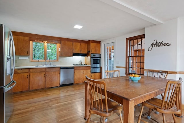 kitchen featuring backsplash, sink, stainless steel appliances, and light hardwood / wood-style floors