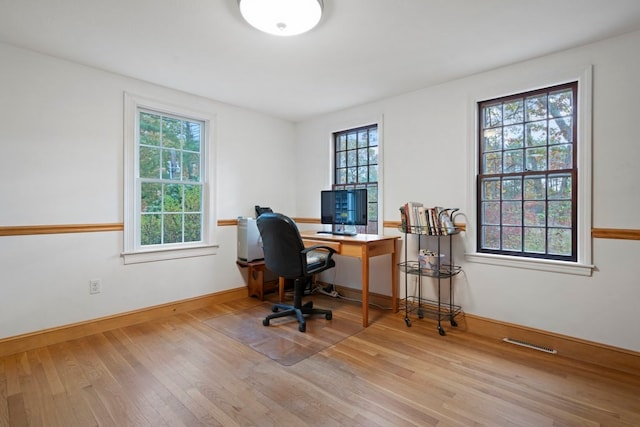 office area with light hardwood / wood-style flooring and a healthy amount of sunlight