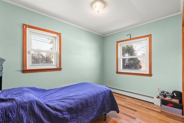 bedroom with ornamental molding, a baseboard radiator, and light wood-style floors