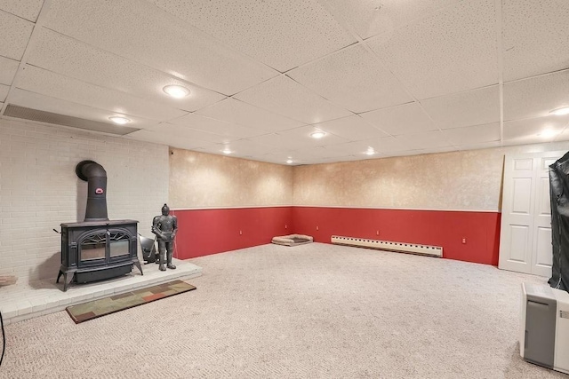 exercise area featuring a paneled ceiling, a baseboard radiator, a wood stove, carpet floors, and recessed lighting