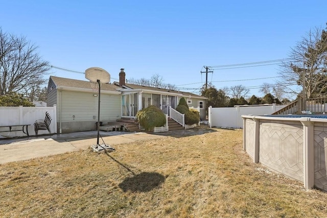 back of property with entry steps, a lawn, a fenced backyard, and a fenced in pool