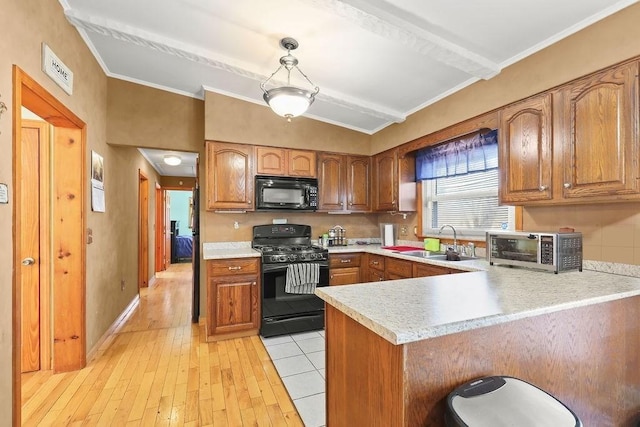 kitchen with decorative light fixtures, light countertops, brown cabinetry, a peninsula, and black appliances