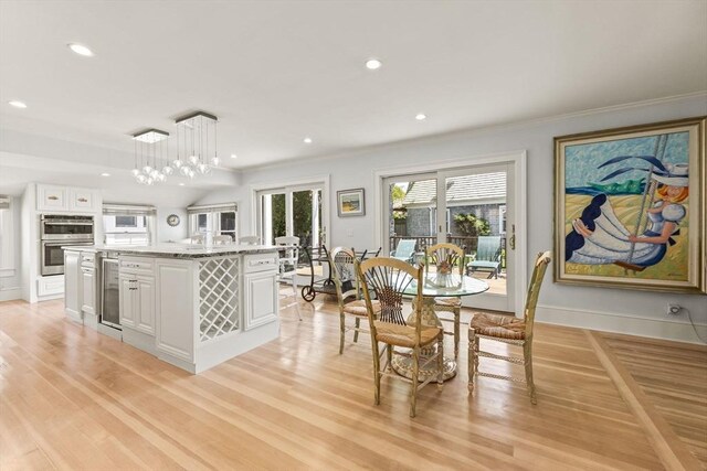 dining space featuring light wood finished floors, ornamental molding, recessed lighting, beverage cooler, and baseboards