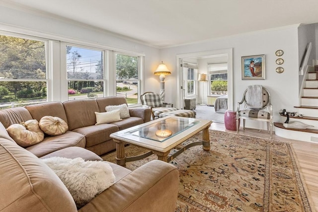 living area featuring wood finished floors, ornamental molding, and stairway