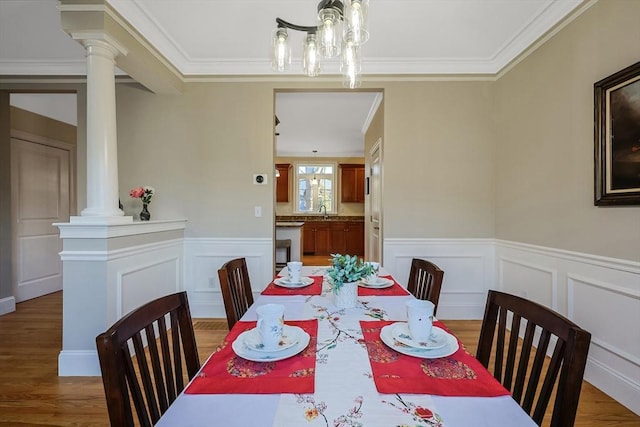 dining room featuring hardwood / wood-style floors, sink, crown molding, and decorative columns