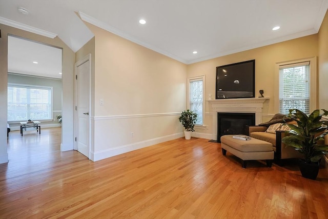 living room featuring light wood-type flooring, a wealth of natural light, and crown molding